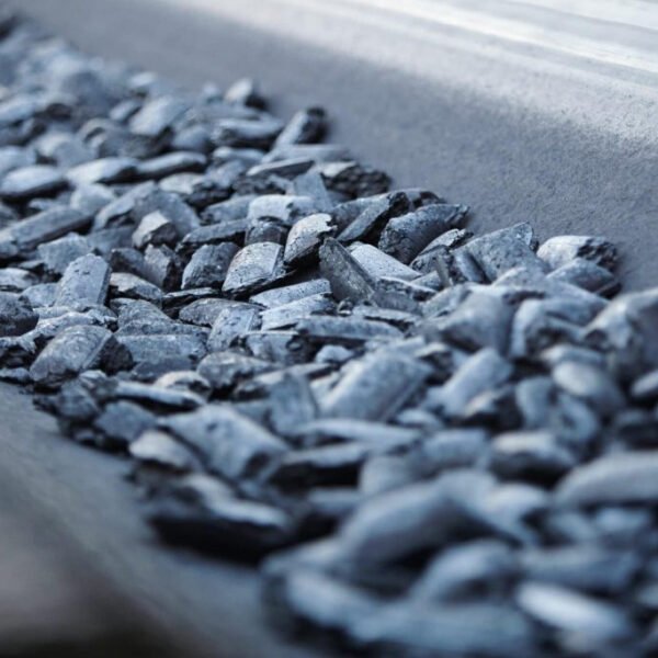 Hot iron briquettes moving on a factory conveyor belt during production, glowing with residual heat.