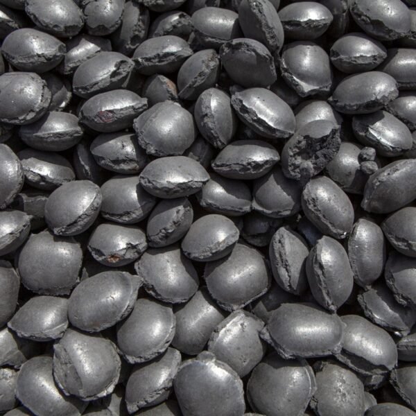 Close-up view of piled iron briquette pellets, showcasing their dense, metallic texture and compact granular form.