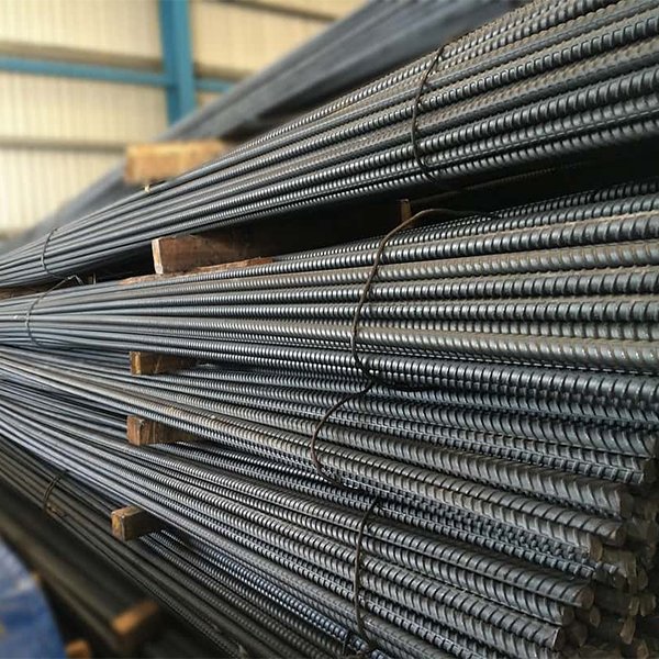Stack of deformed rebars with visible mill markings and ASTM/BS codes