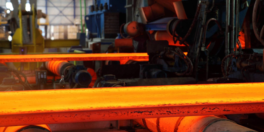 glowing hot steel slab being processed in a factory