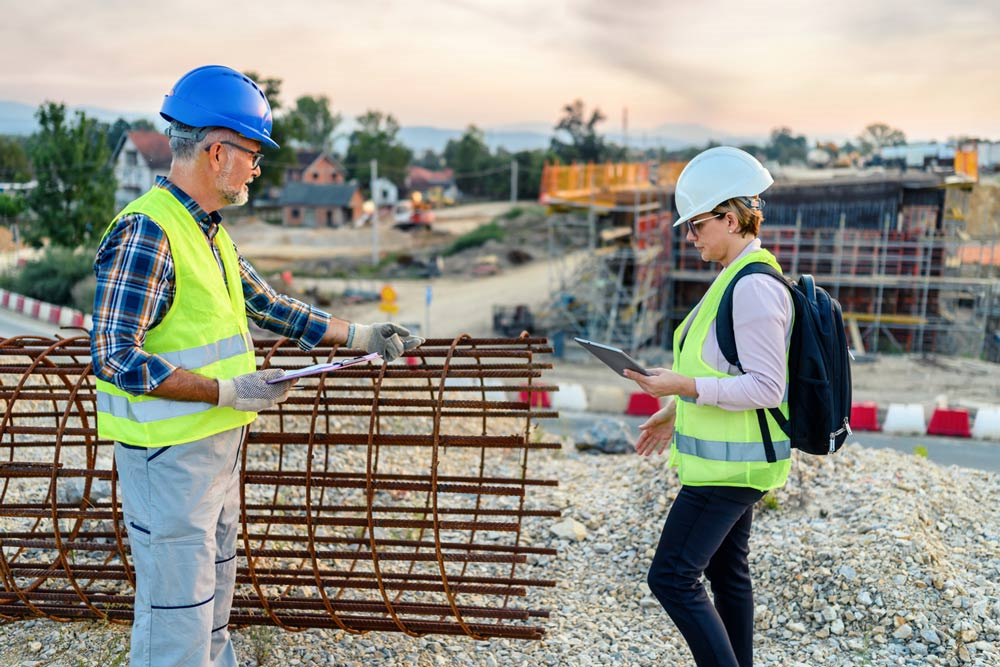 2 workers wearing protective gear examining an steel rebar concrete reinforcement
